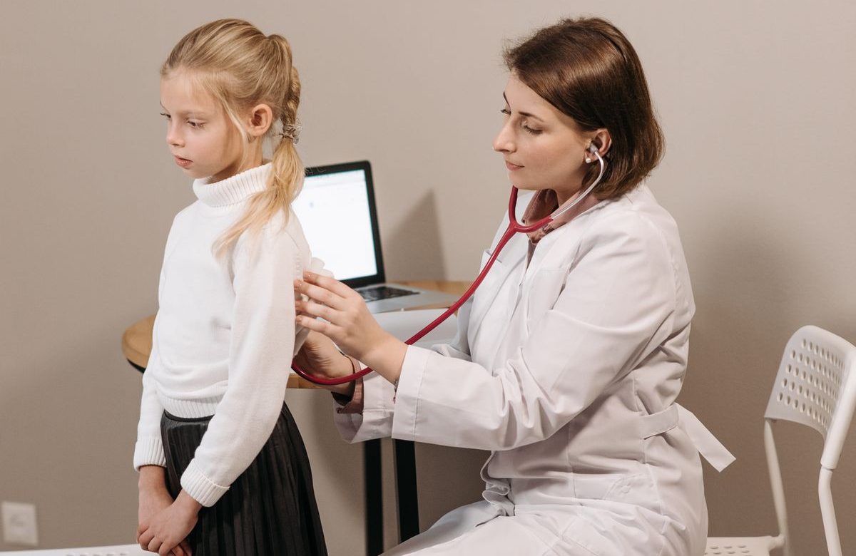 Pediatra revisando a una niña con estetoscopio en control de crecimiento